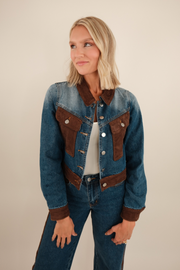 Medium-wash cropped denim jacket with brown suede contrast panels on collar, chest pockets, hem, and cuffs, western-inspired style.