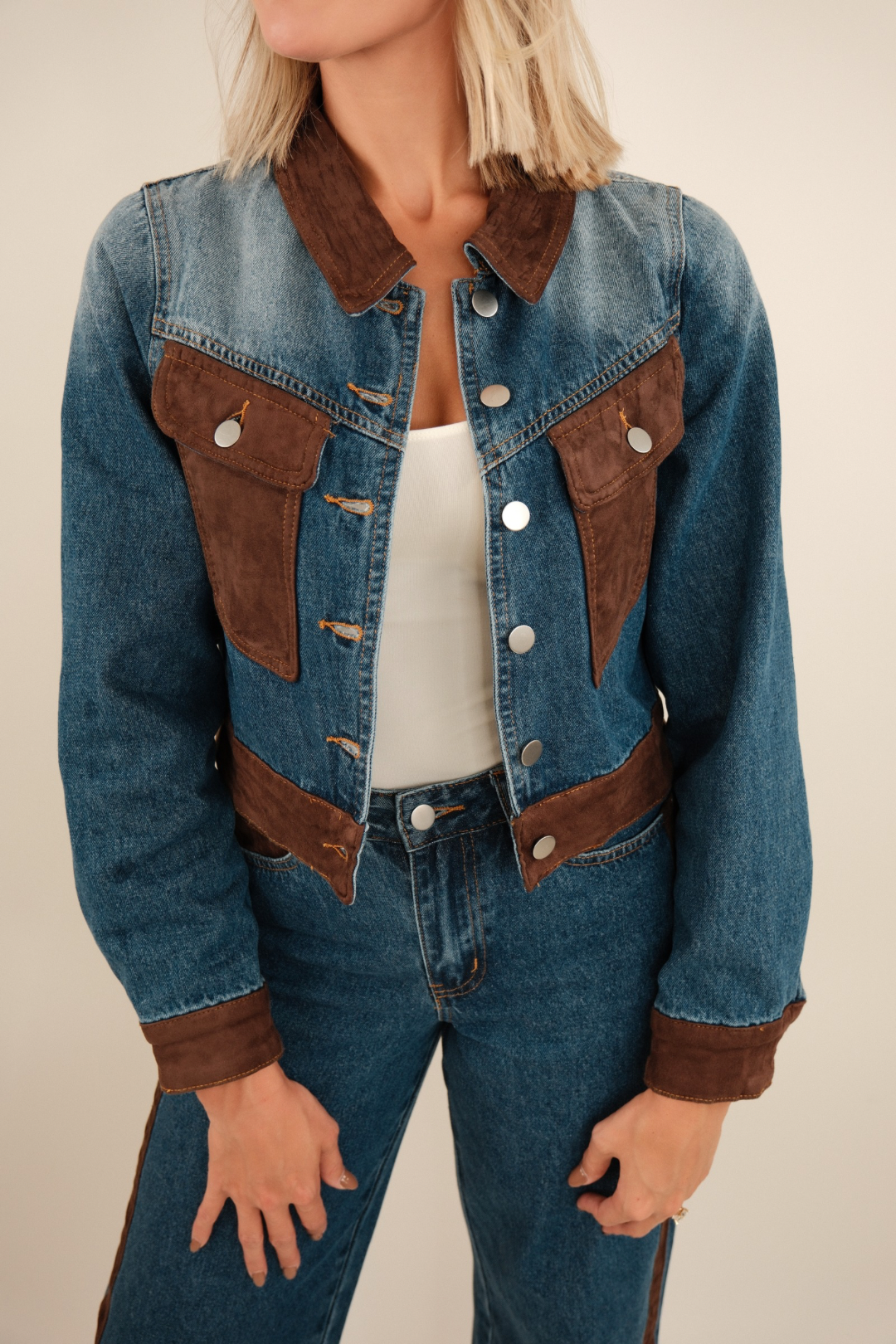 Close-up of cropped denim jacket highlighting suede collar and chest pocket details with contrast stitching.