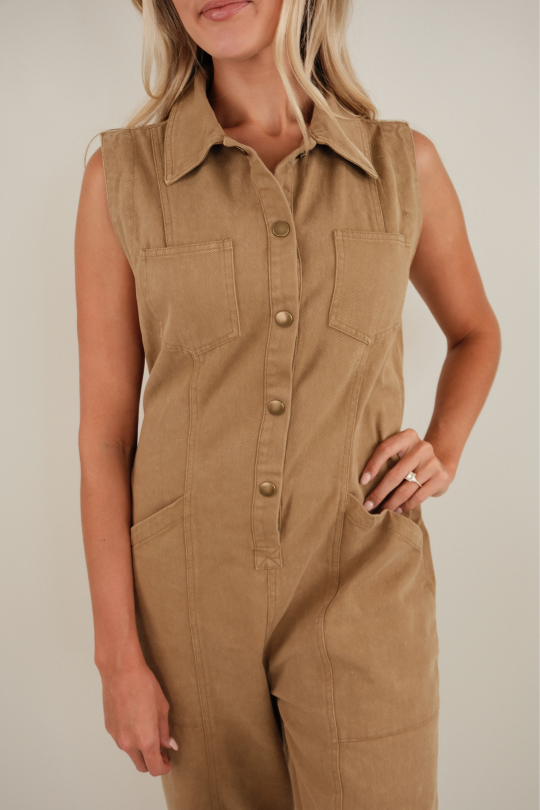 Woman wearing a brown jumpsuit against a plain background