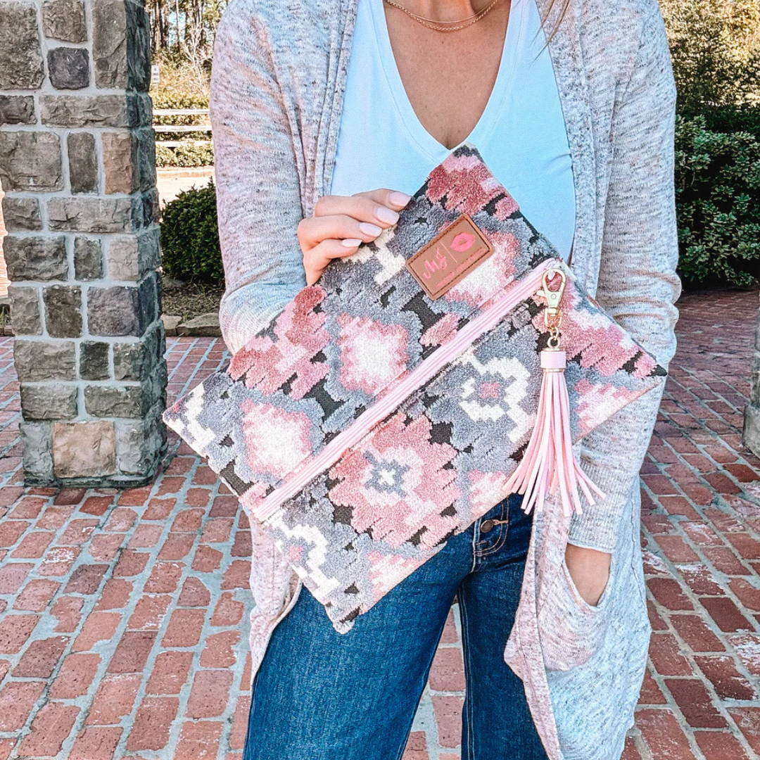 Styled Aztec Blush Makeup Junkie bag next to travel essentials, showing velvet exterior, blush zipper, and blush‑pink interior pop.