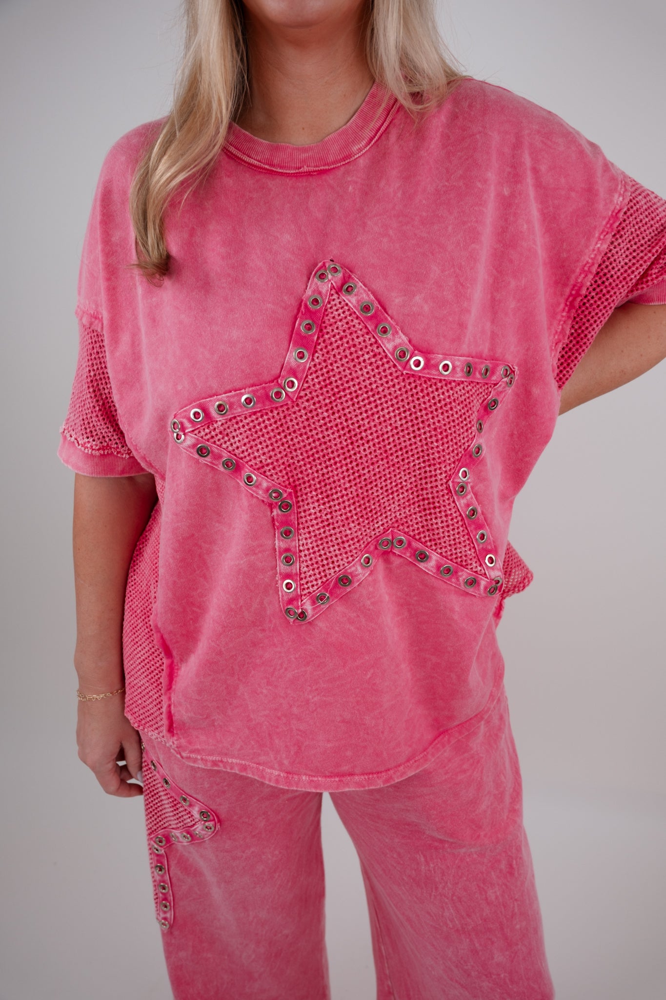 Person wearing a pink outfit with a star design on a plain background