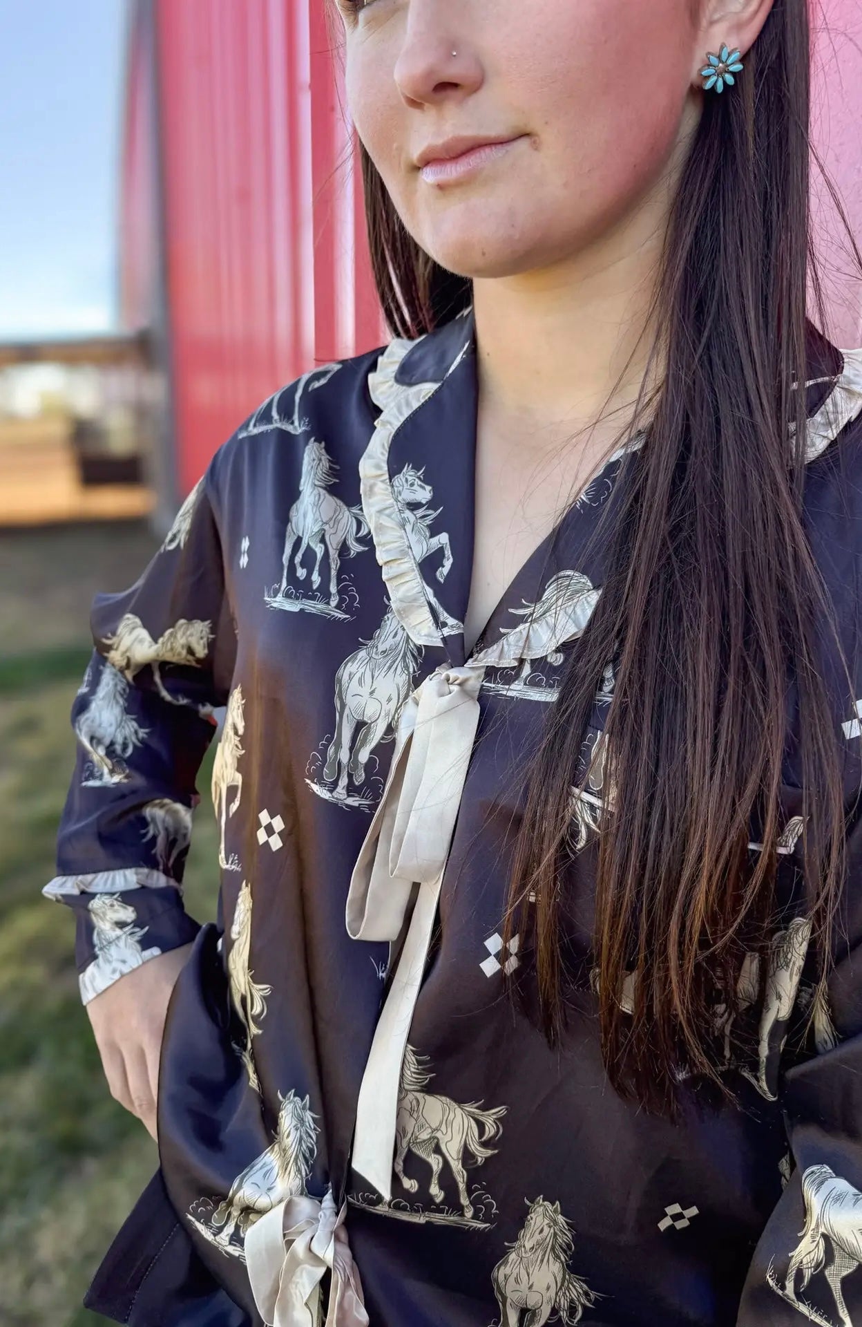 Woman wearing a black pajama set with horse print in an outdoor setting