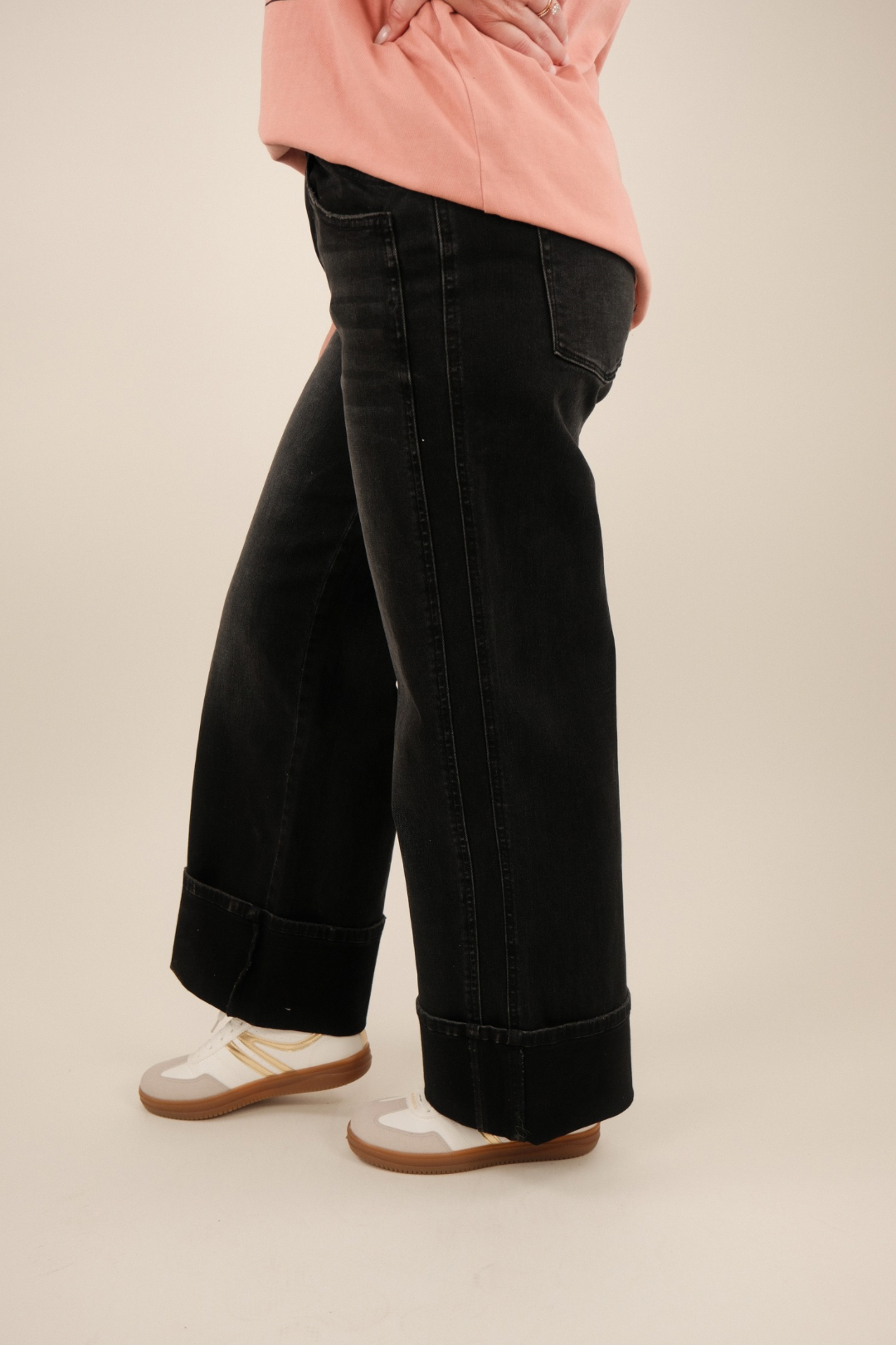 Side view showcasing baggy, wide‑leg cuffed silhouette, double pockets and relaxed fit in washed black denim with western utilitarian edge.