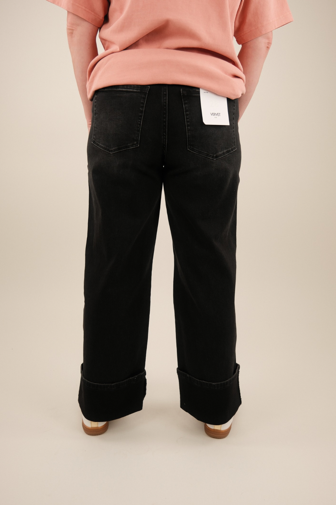 Rear view of super high‑rise utility jeans featuring clean back pockets, relaxed fit and wide cuffed hems in vintage black denim.