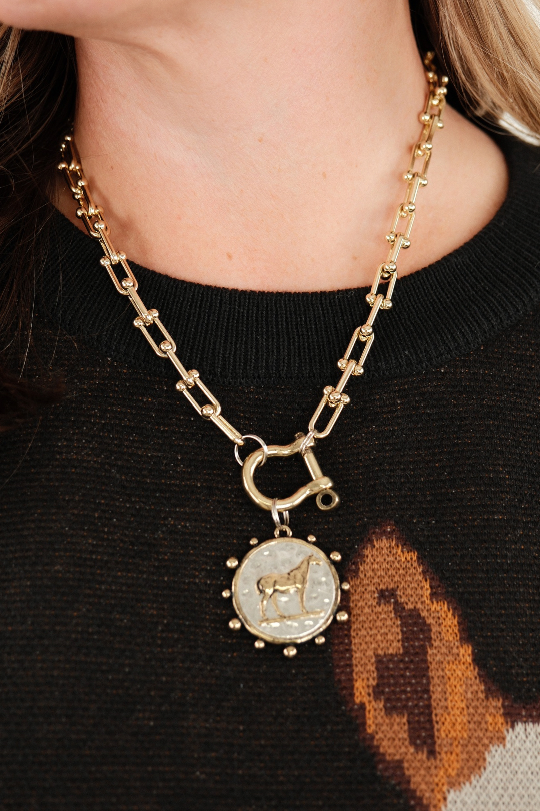 Close-up of Bridle Path Pendant Necklace in gold highlighting detailed horse pendant with circular edge accents and western-inspired chain links.