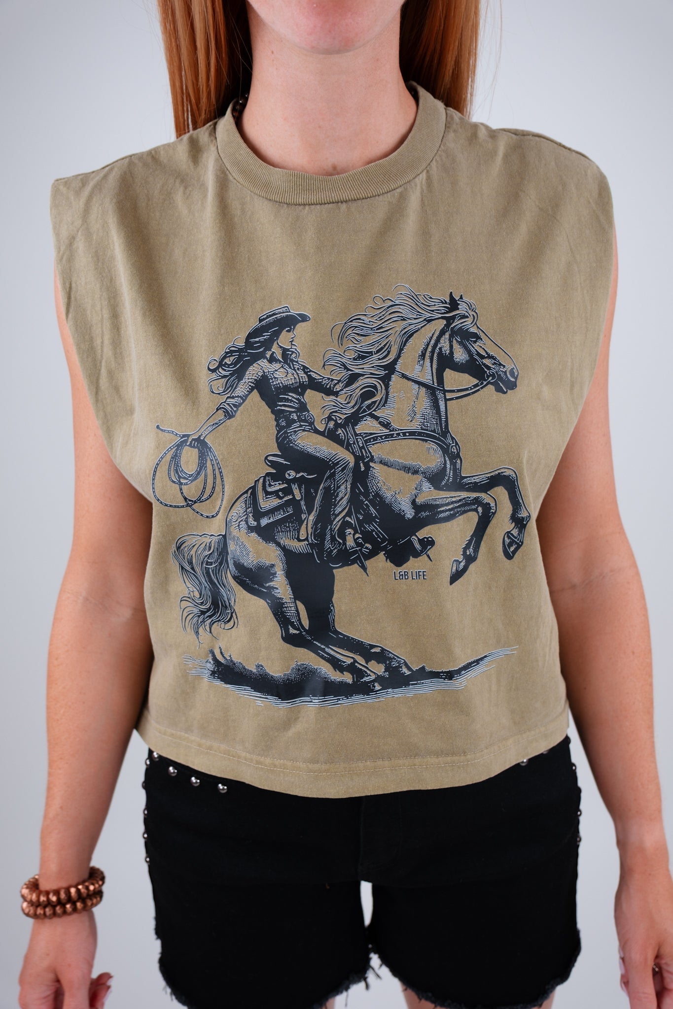 Person wearing a sleeveless green top with a graphic of a rider on a horse.