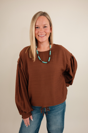 Front view of Bronco Brown Blouse in warm chocolate with rounded neckline, bubble sleeves and western-inspired design.