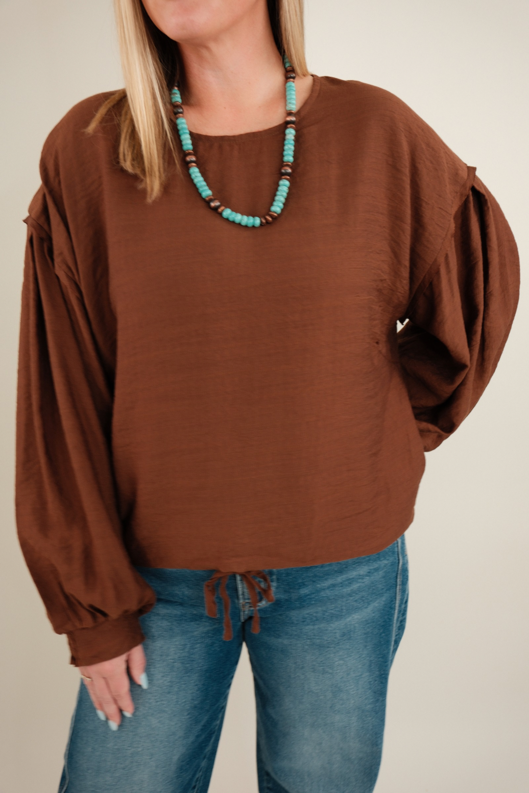 Close-up of Bronco Brown Blouse highlighting textured brown fabric, rounded neckline and puffed bubble sleeve detail.