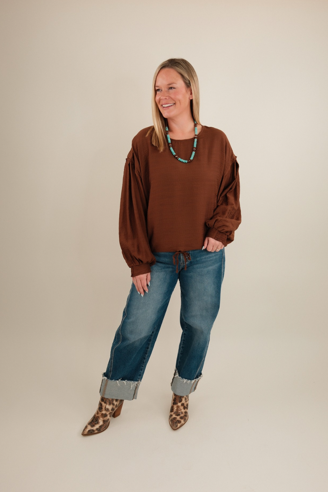 Full body shot of model in Bronco Brown Blouse with rounded neckline and bubble sleeves styled with denim for cowgirl chic.
