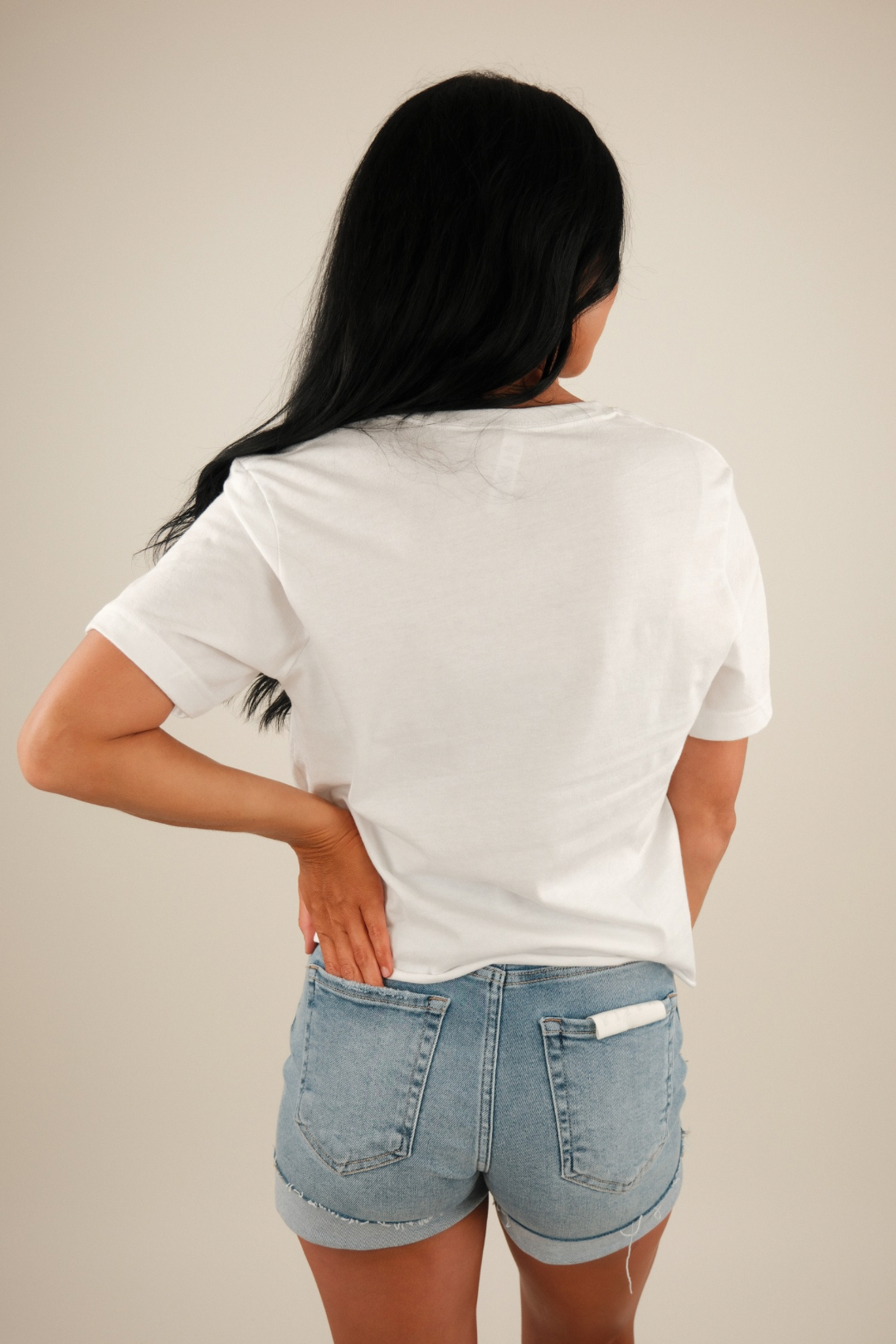 Person wearing a white t-shirt and denim shorts against a plain background