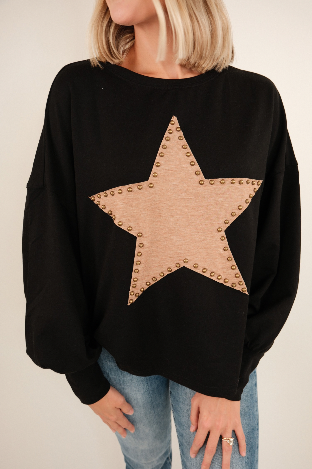 Front view of Bronze Star Pullover, black knit sweater with brown star motifs, bronze studded embellishments, and relaxed western fit.