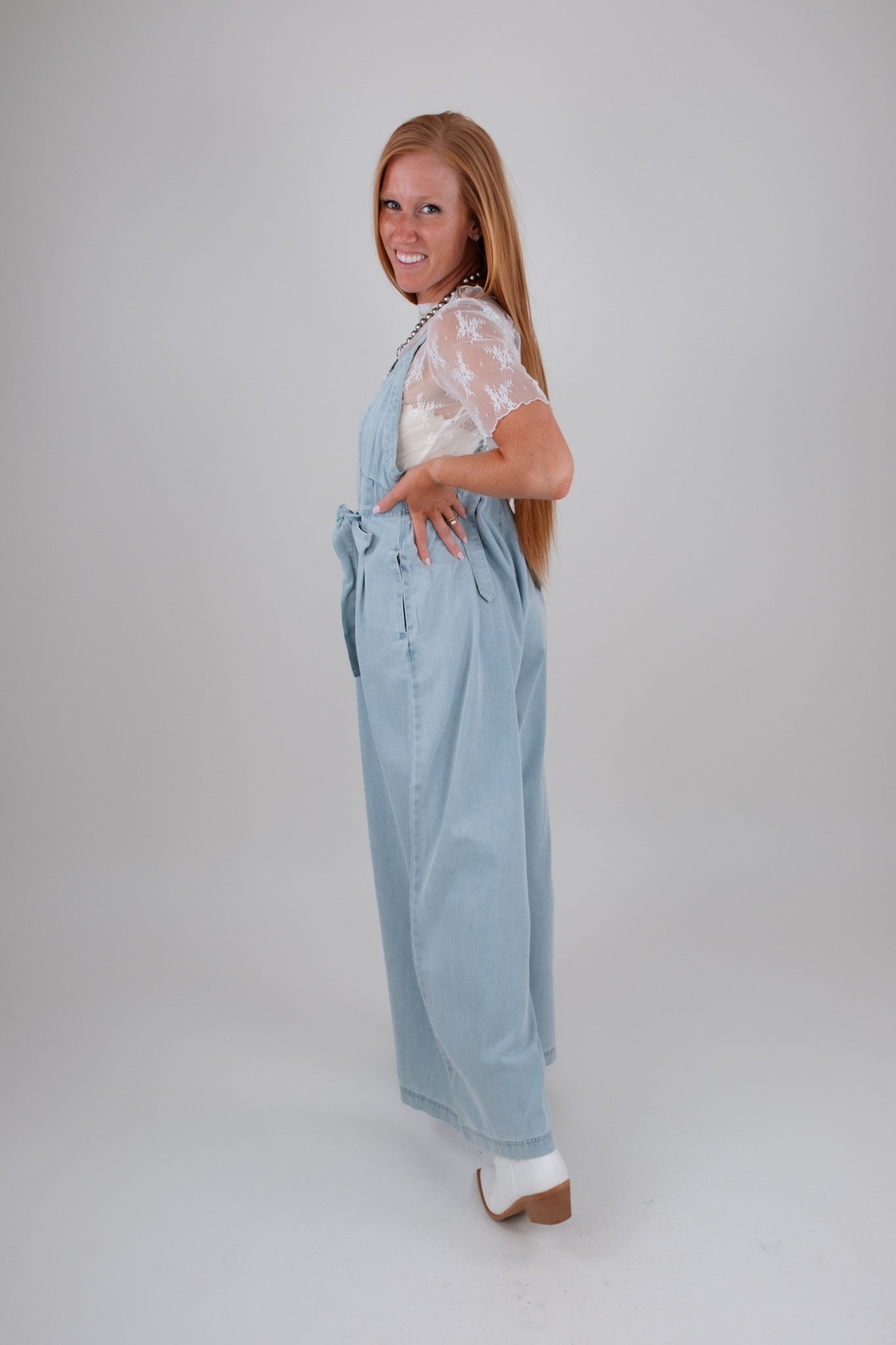 Woman wearing light blue overalls on a white background