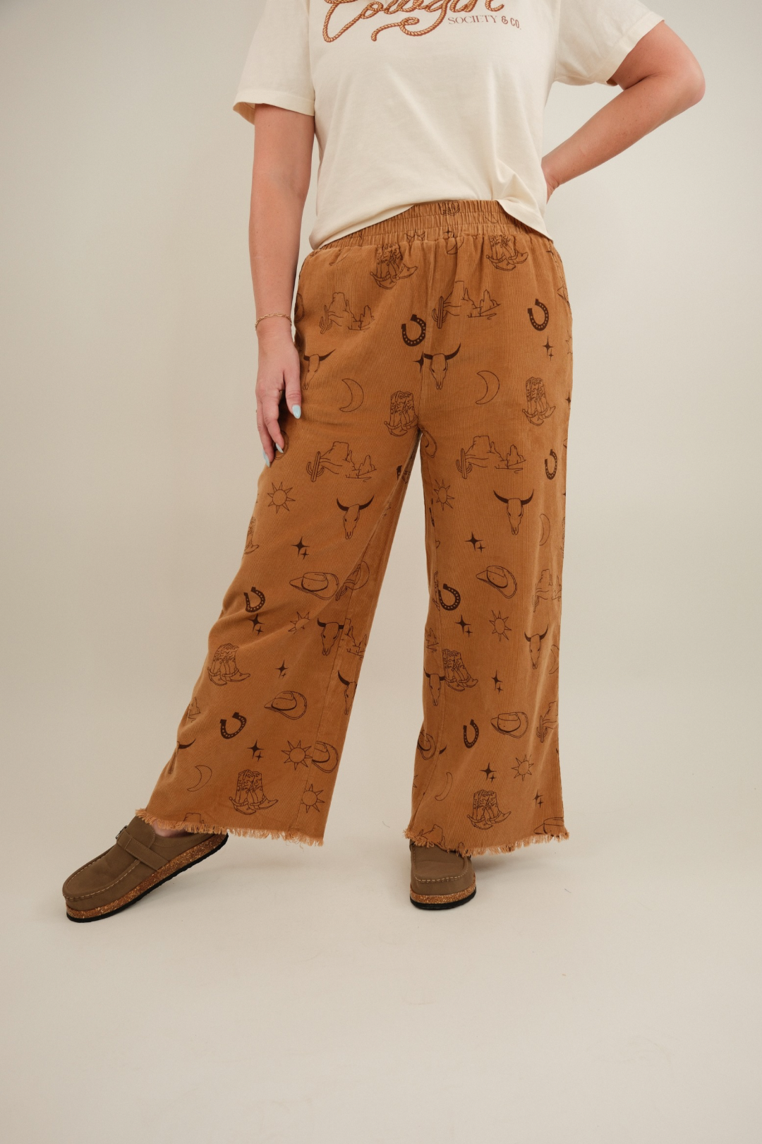 Close-up of camel Canyon Creek Corduroy Pants highlighting corduroy fabric texture and western print details.