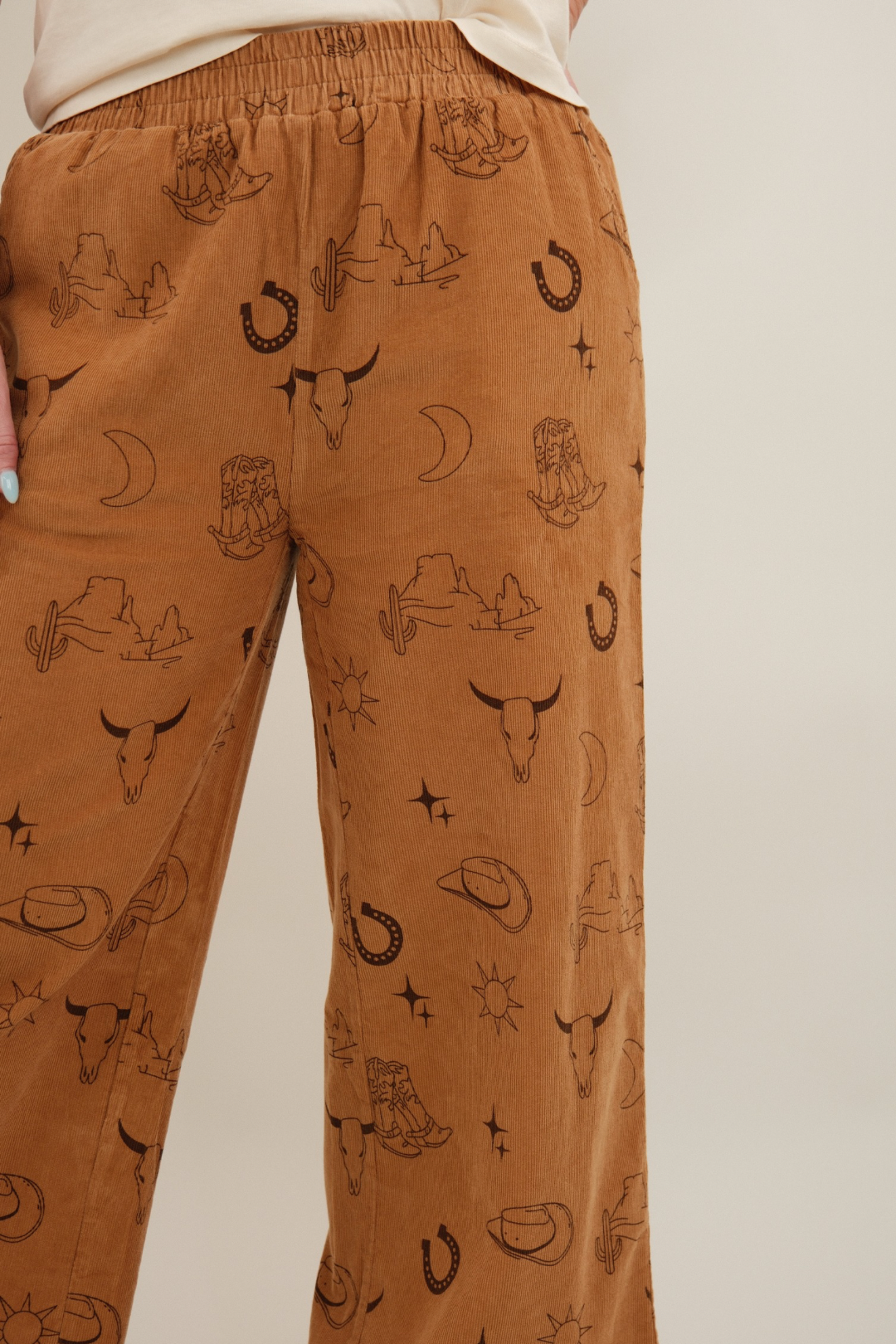 Close-up of camel Canyon Creek Corduroy Pants highlighting corduroy fabric texture and stitched western motif.