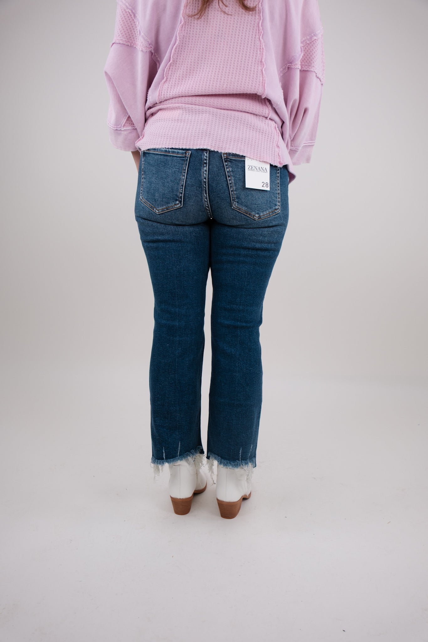 Person wearing blue jeans and a pink sweater on a plain background