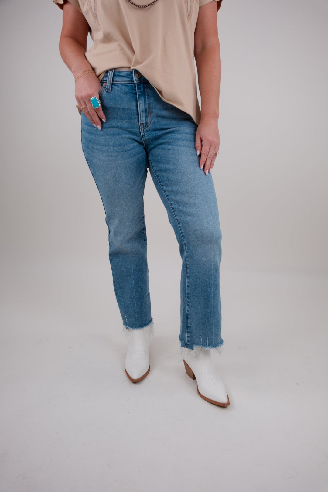 Person wearing blue jeans and white boots on a plain background
