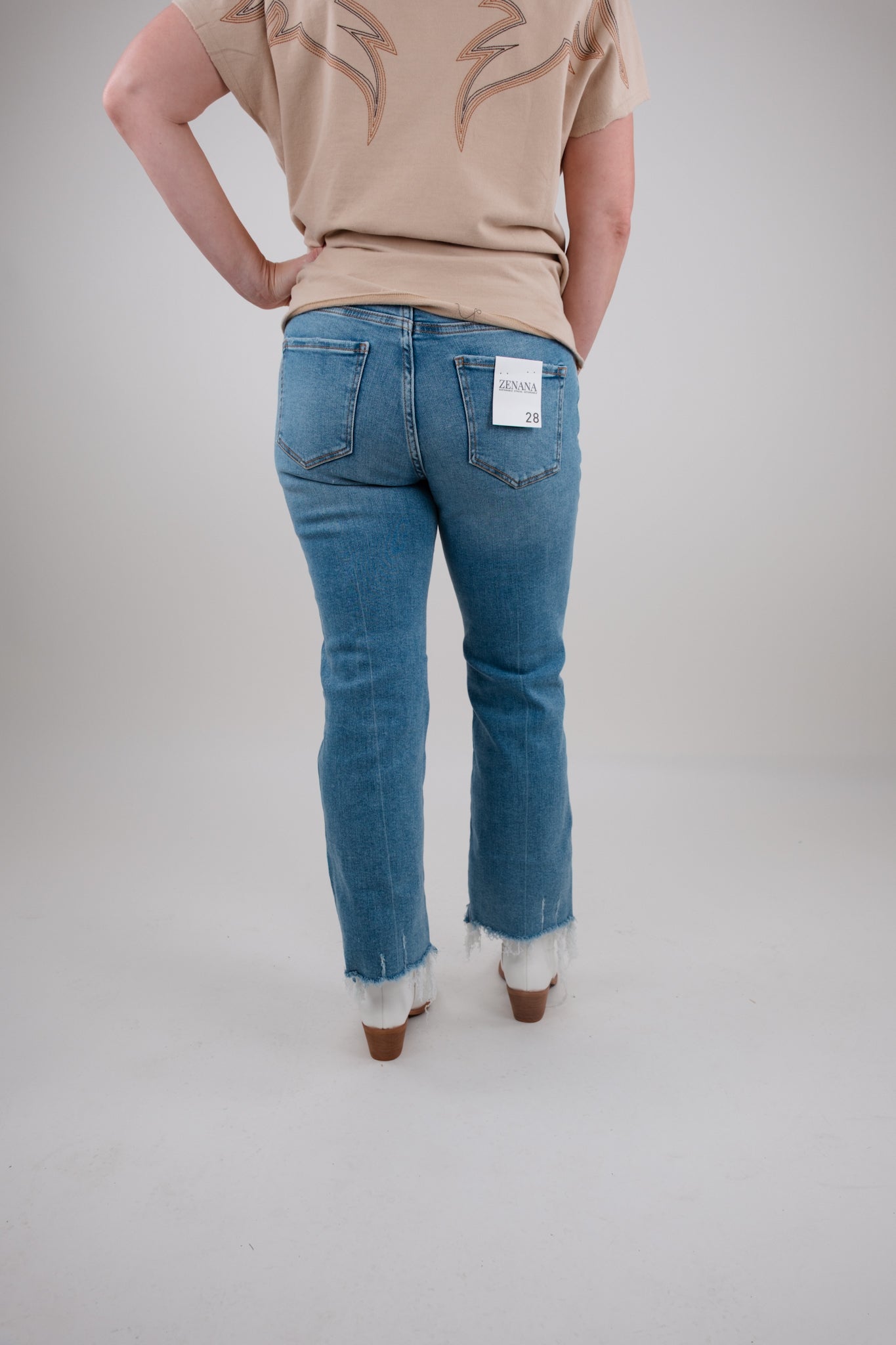 Person wearing blue jeans and a beige shirt on a plain background