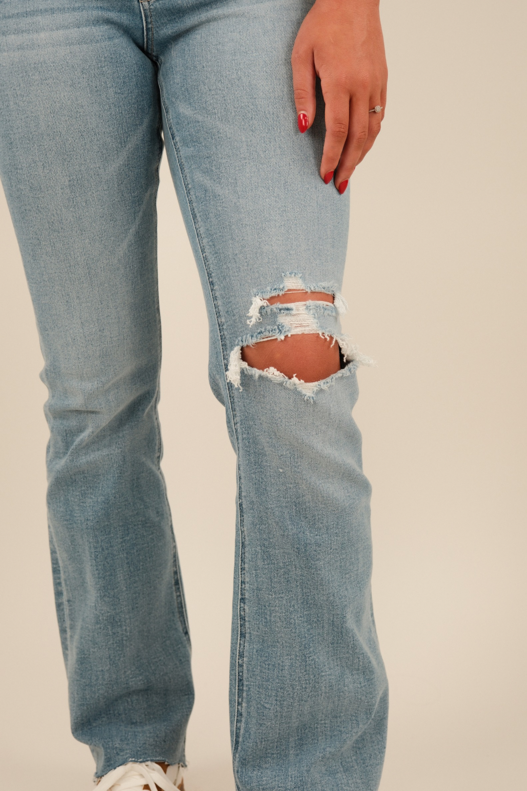Close‑up of distressed knee light‑wash denim jeans