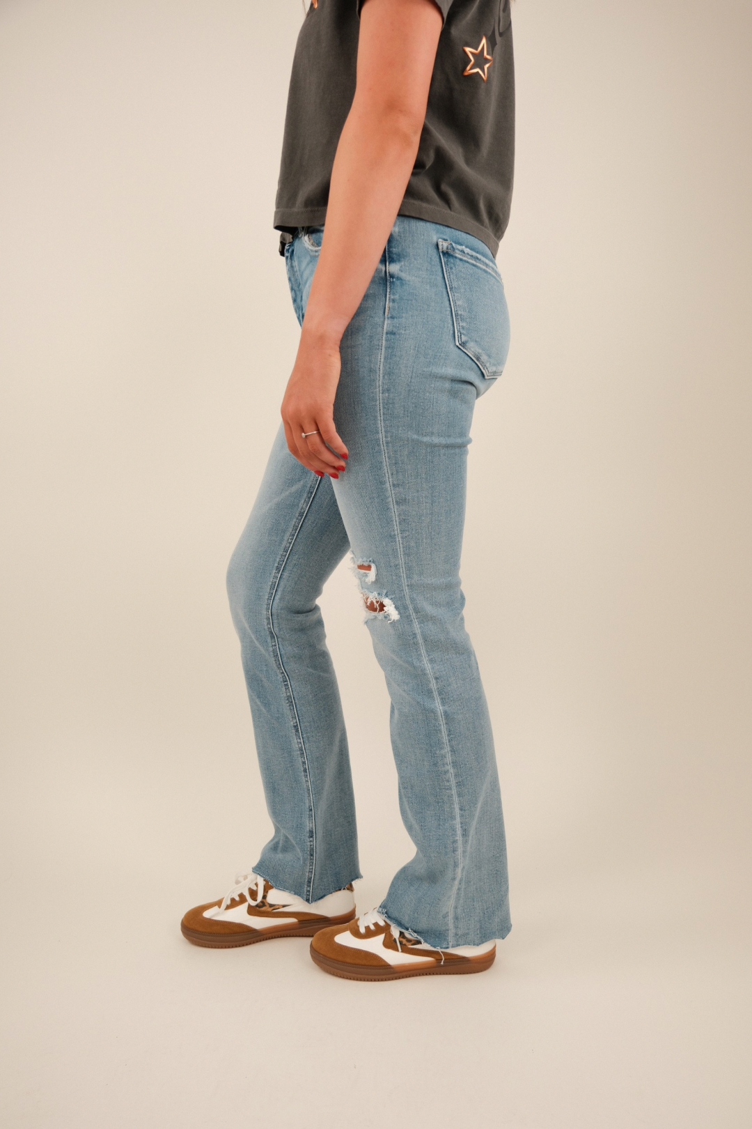 Side profile of light‑wash denim jeans highlighting straight bootcut leg and knee distressing