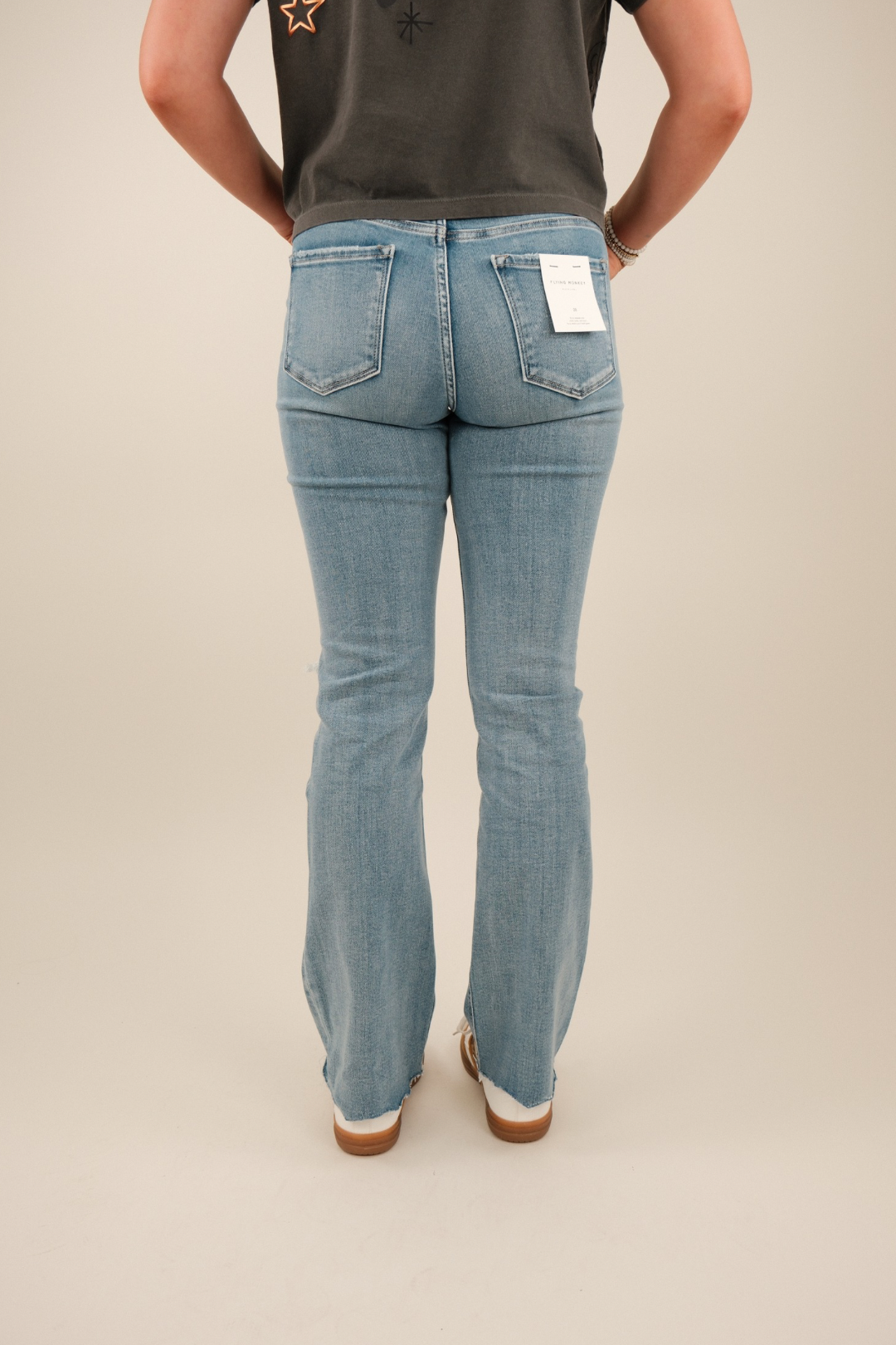 Back view showing pointed Western yoke, faded detailing, and raw hemline of light‑wash denim jeans.