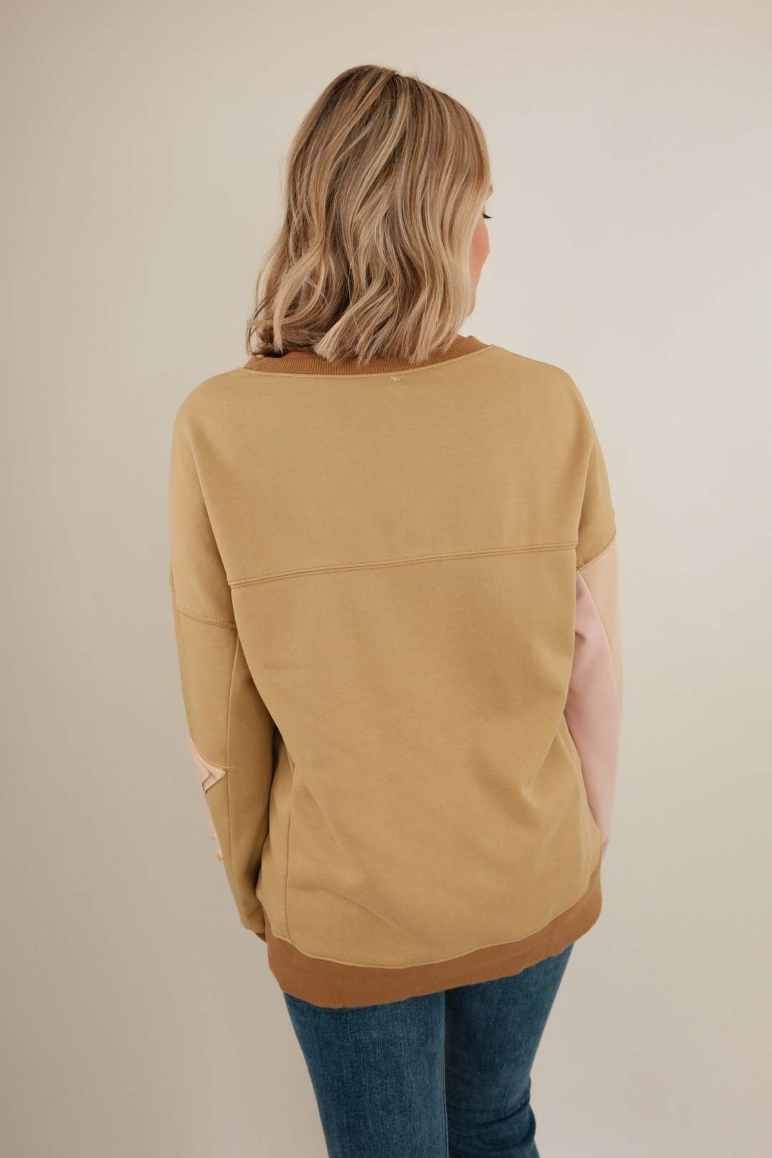 Back view of Cosmic Cowgirl Pullover in tan, lightweight knit with relaxed fit and side slit hem detail.