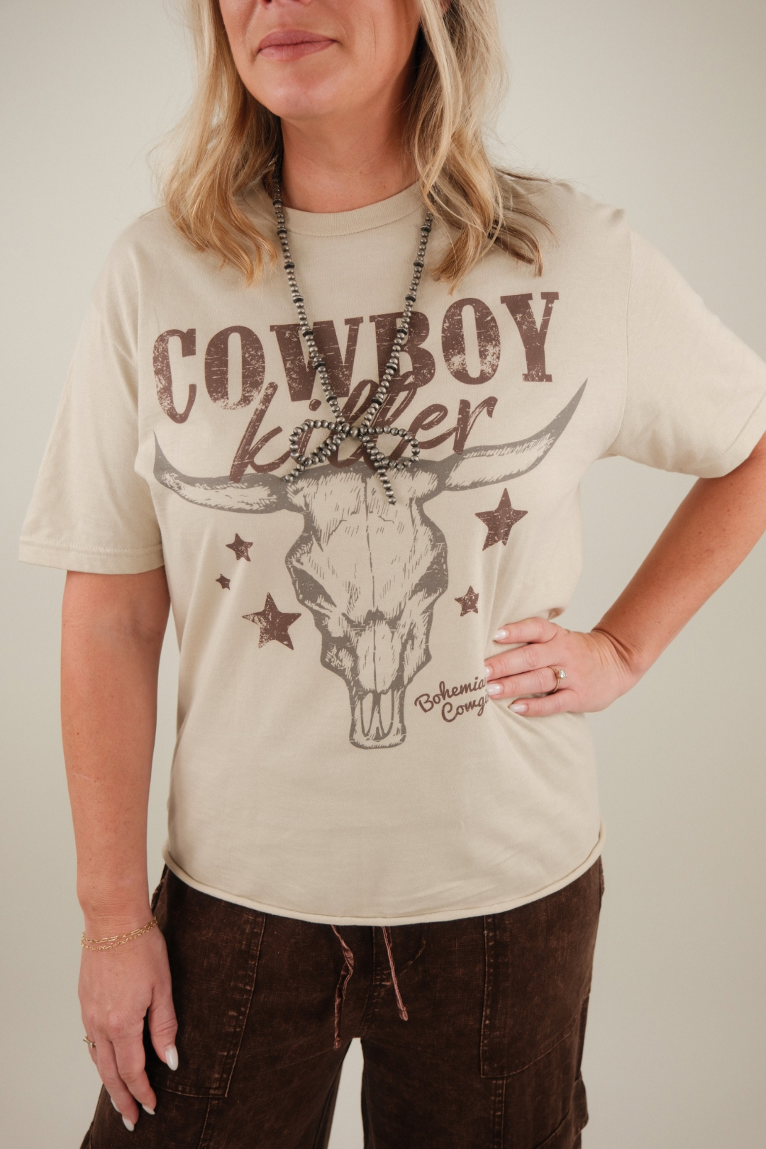 Woman wearing a cream t-shirt with 'Cowboy Killer' bull skull design