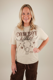 Woman wearing a t-shirt with 'Cowboy Killer' design on a plain background