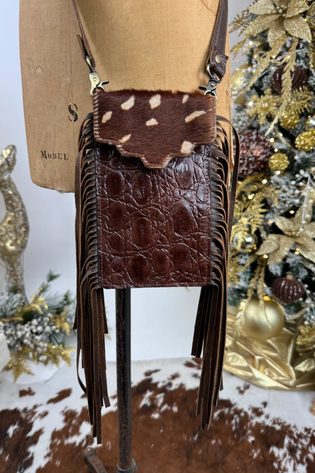 Brown leather handbag with fringe on a mannequin against a decorative background