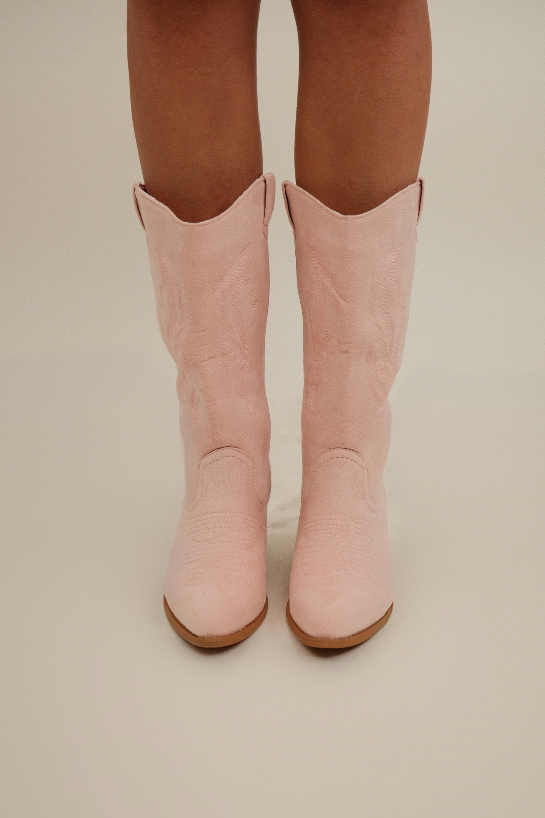Front view of Cowgirl Pop Suede Boots, soft light pink suede with decorative embroidery and mid-height heel.