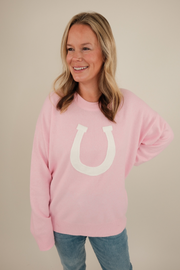 Front view of blush pink Cowgirl’s Luck Sweater, ultra-soft knit with cream horseshoe design and feminine western cowgirl flair.