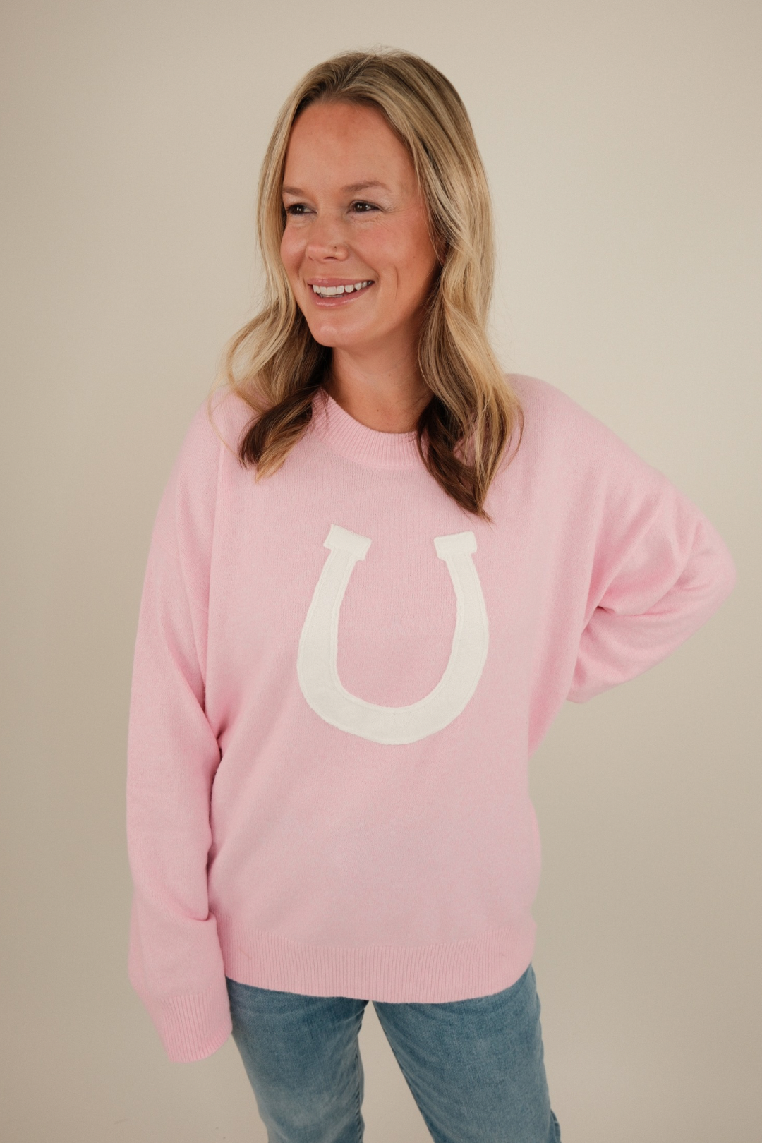 Front view of blush pink Cowgirl’s Luck Sweater, ultra-soft knit with cream horseshoe design and feminine western cowgirl flair.