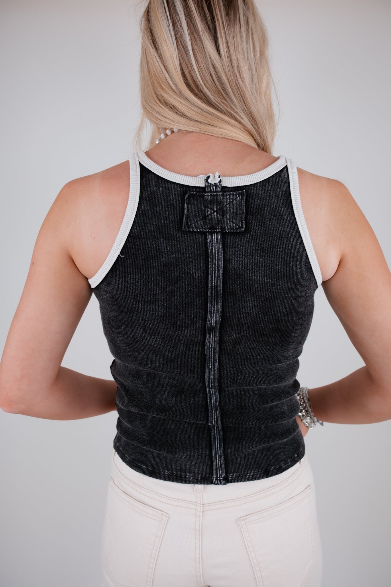 Person wearing a black tank top with white trim on a plain background