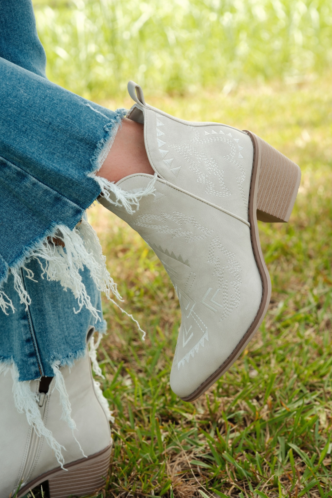 Close-up of Aztec embroidery detail on tan suede bootie shaft, highlighting intricate southwestern stitching and tonal textures.