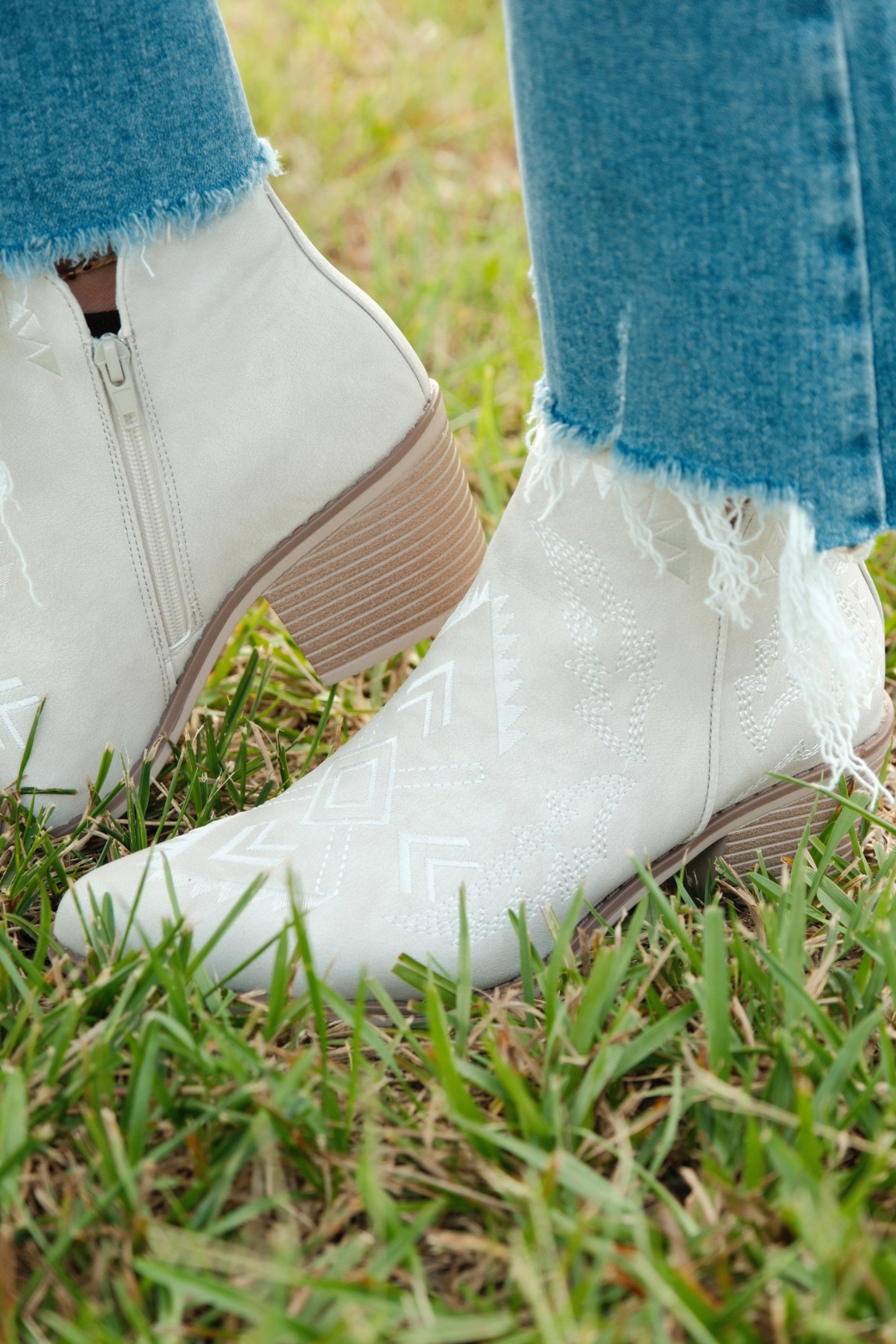Close-up of Aztec embroidery detail on tan suede bootie shaft, highlighting intricate southwestern stitching and tonal textures.