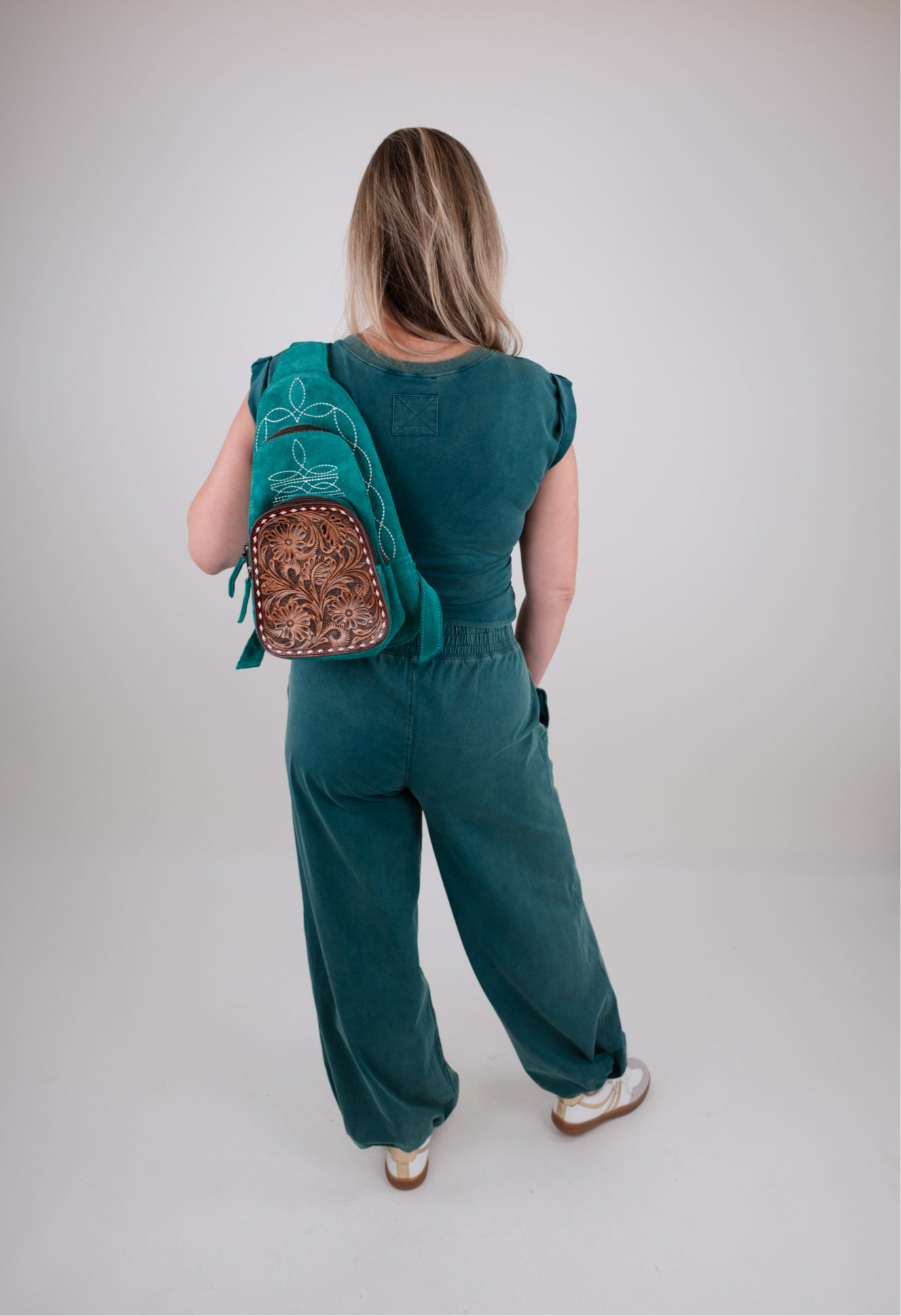 Person wearing a green outfit set with a matching backpack on a plain background
