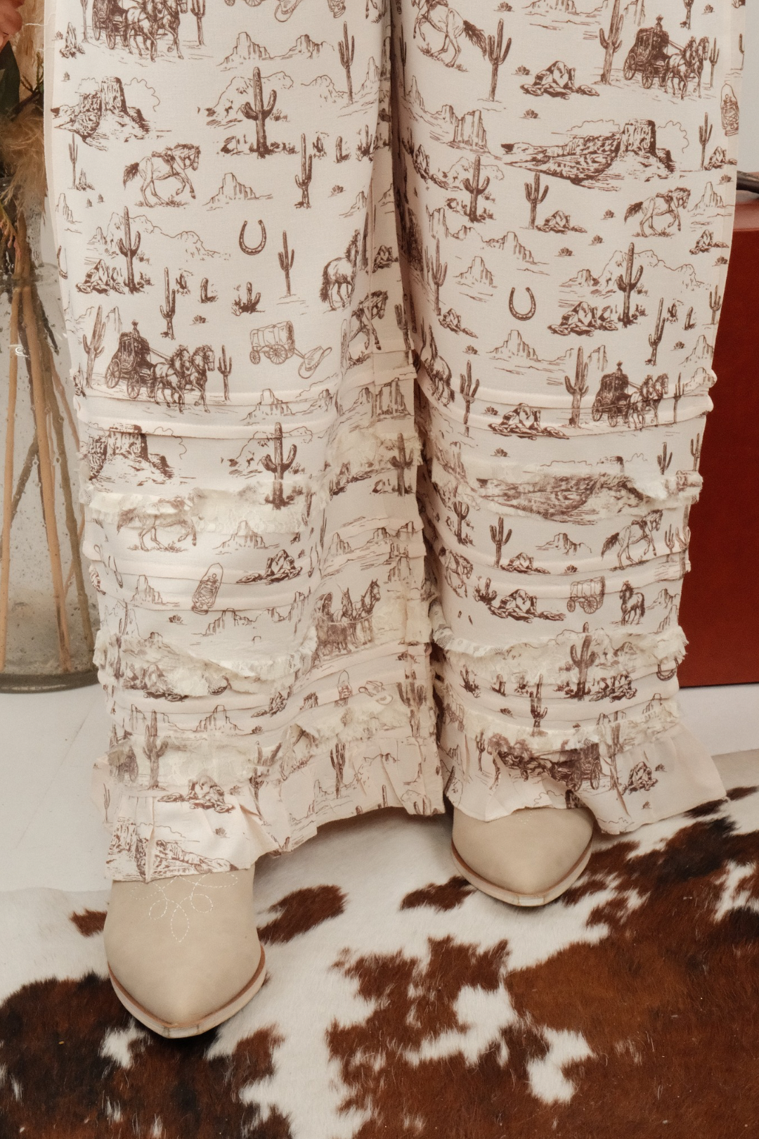 Person wearing western patterned pants with ruffles on a cowhide rug