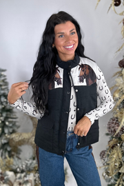 Woman wearing a black horse vest over a patterned shirt with Christmas decorations in the background
