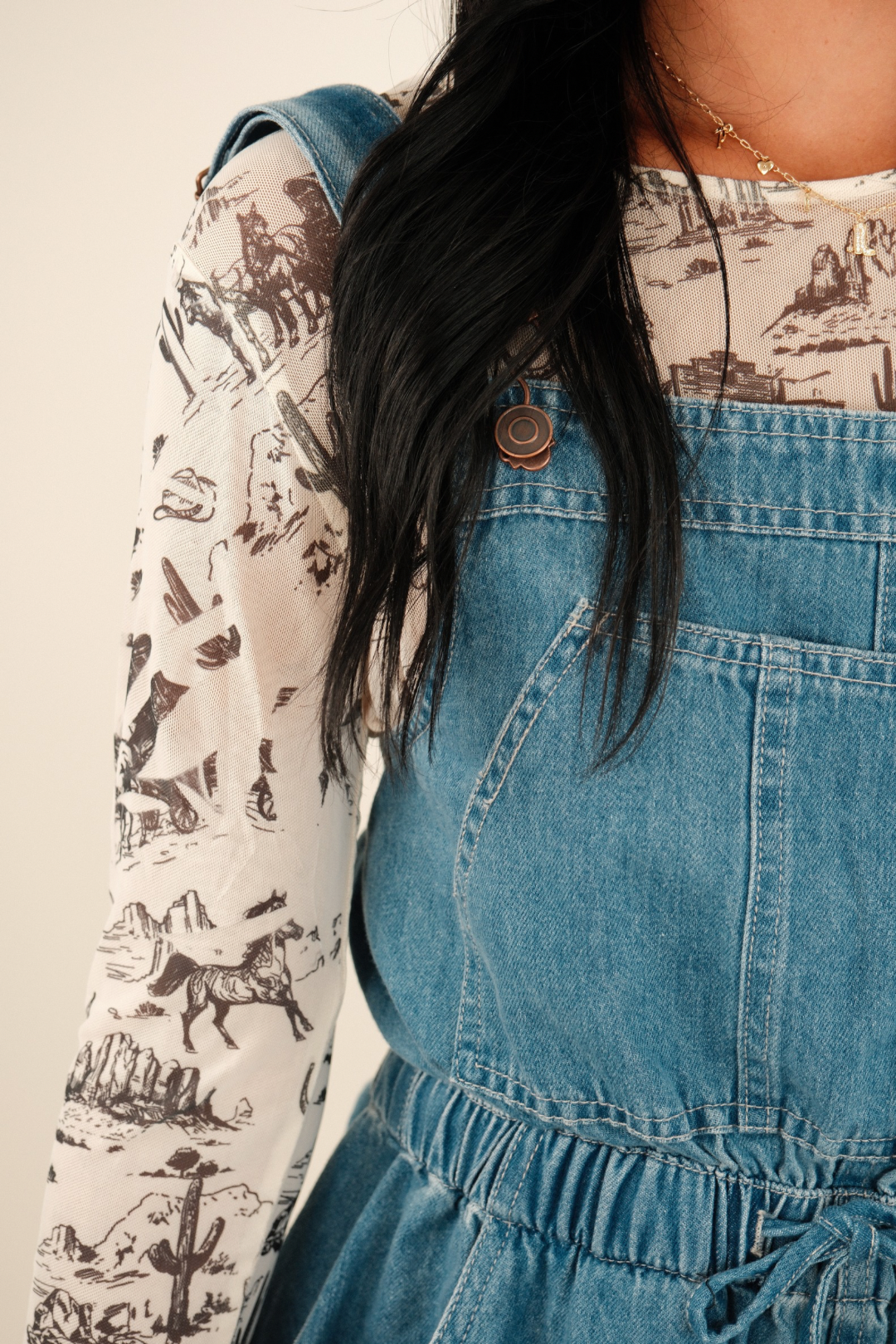 Close‑up of the mesh fabric revealing cowboy boots, cacti, horses and hats in browns, tans and grays on black mesh top.