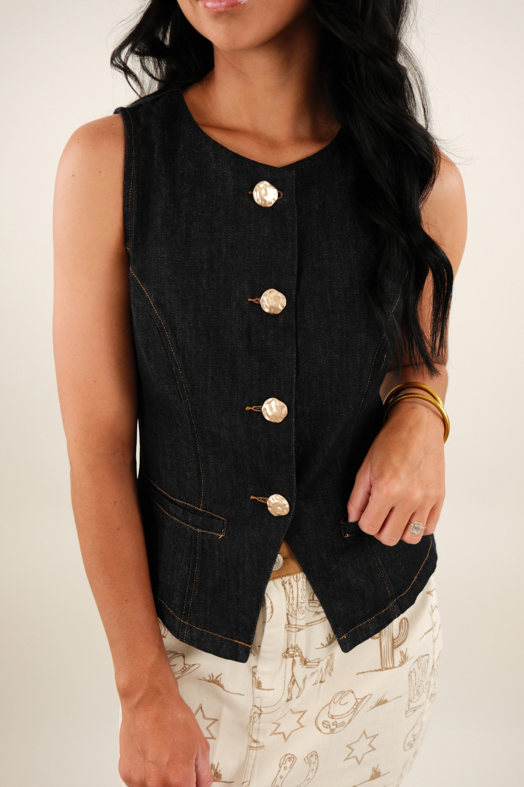 Close-up of Golden Range Denim Vest highlighting brushed gold textured buttons, darted seams and functional pocket detail.