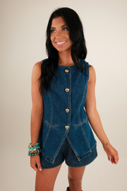Detail of gold button front placket and pointed collar on dark denim vest.