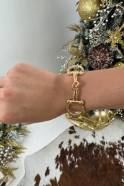 Mixed metal bit bracelet on a wrist with a decorated Christmas tree in the background