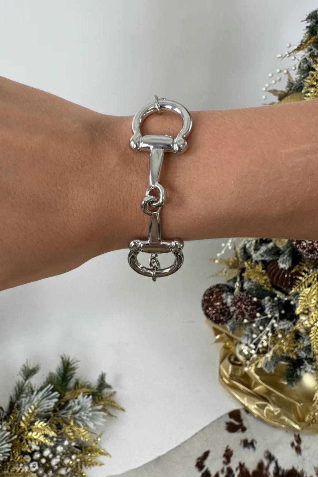 Silver bit bracelet on a wrist with a decorative background