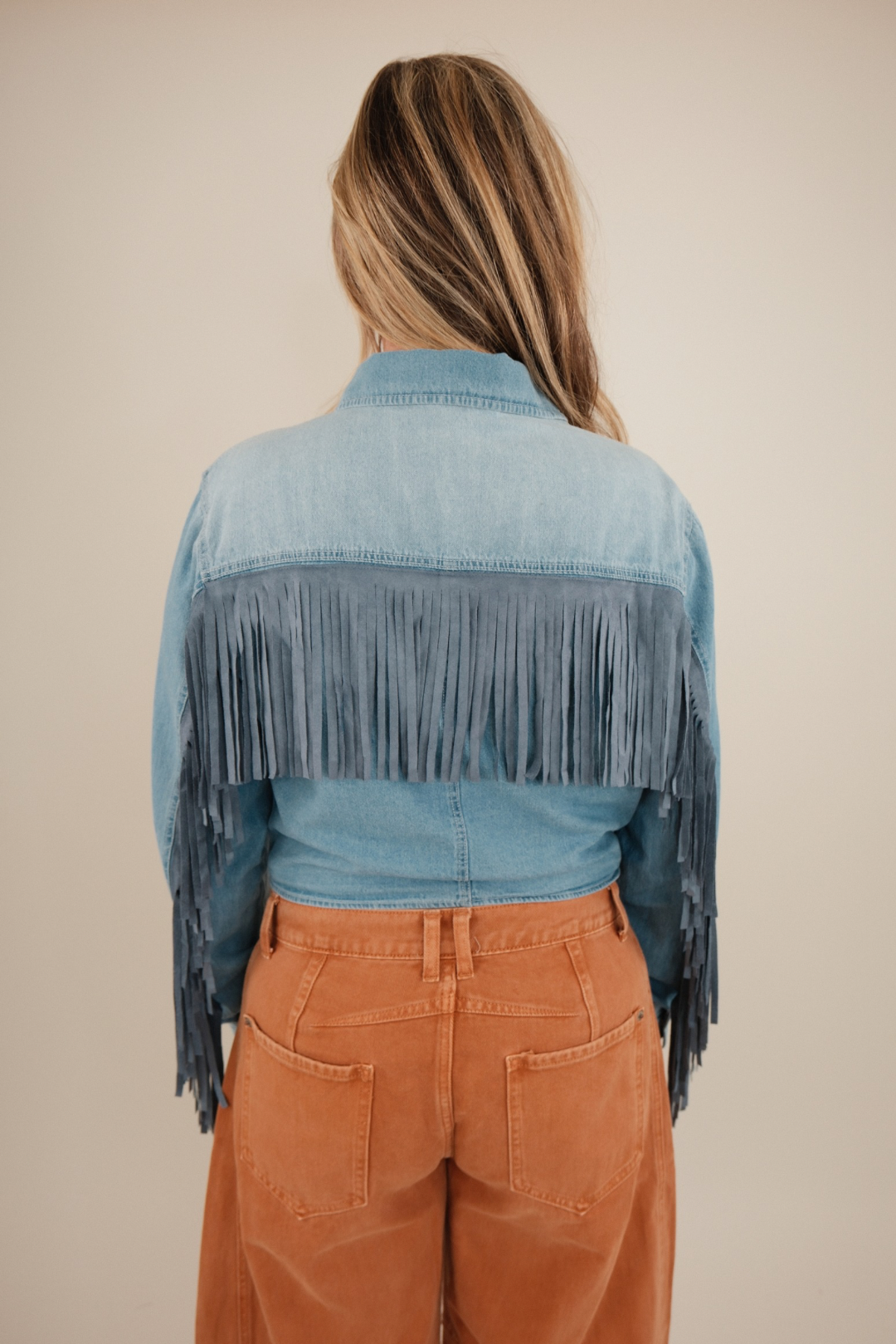 Back view of High Noon Fringe Denim Top, light wash cropped denim shirt with dramatic fringe across back and western cowgirl style.