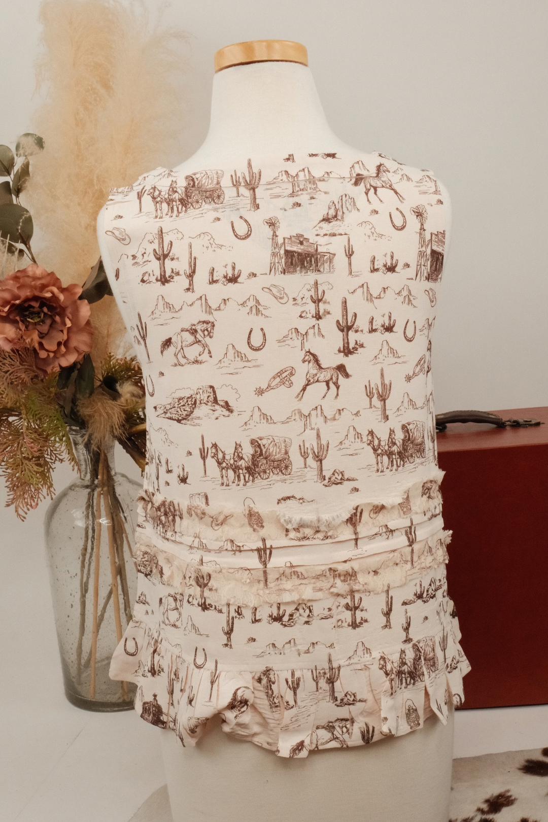 Sleeveless top with western pattern on a mannequin against a neutral background