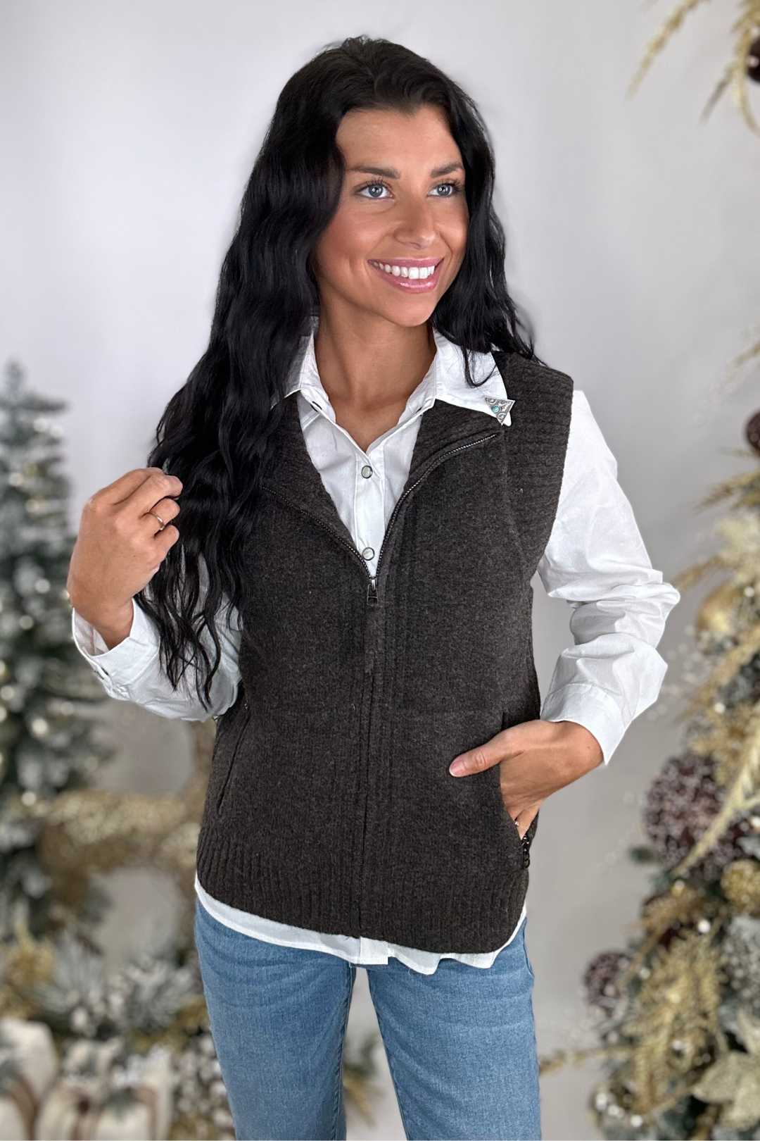 Woman wearing a brown vest over a white shirt with a neutral background