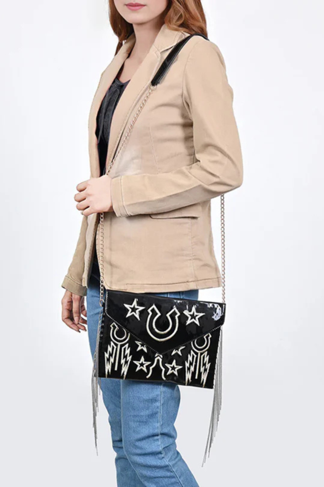 Woman holding a black handbag with star and horseshoe designs against a white background