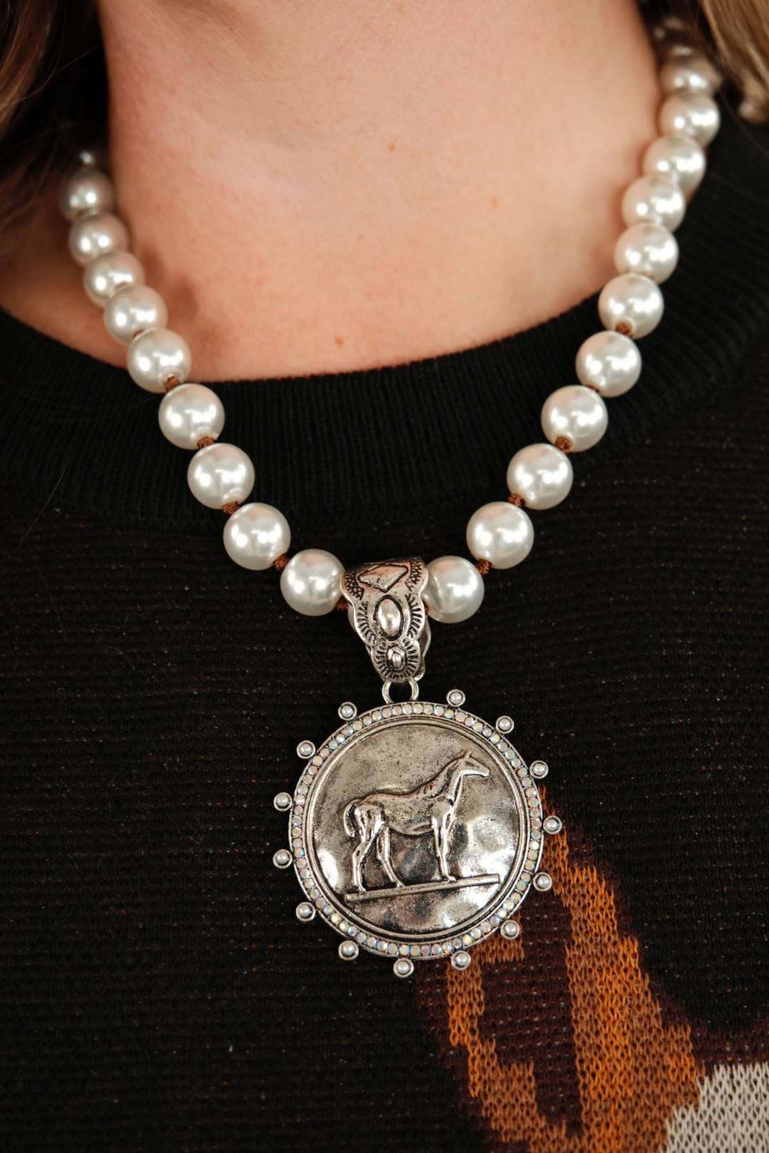 Front view of Iridescent Rider Pearl Necklace with light grey pearls and round horse pendant framed by iridescent stones for elegant western style.