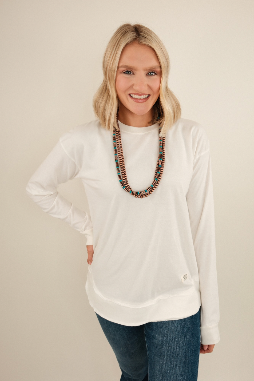 Vintage-washed long sleeve poncho tee in ivory with relaxed drape and western flair.