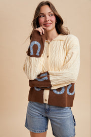 Woman wearing a patterned cardigan with horseshoe designs on a beige background