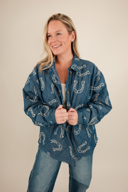 Front view of Lucky Stitch Quilted Denim Jacket, medium wash denim with cream horseshoe print, collared neckline, and quilted texture.